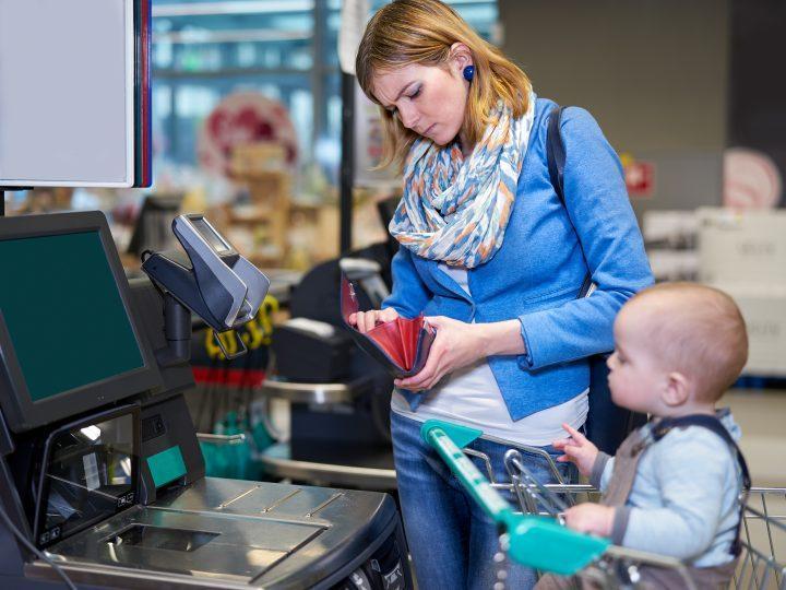 Young woman with baby paying with self checkout